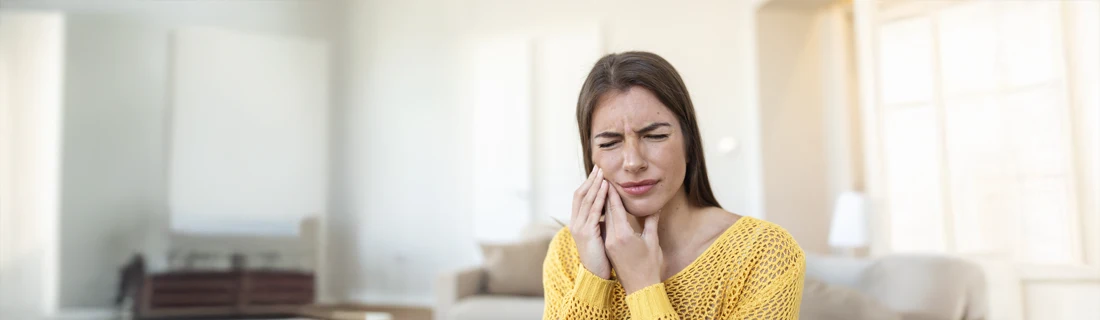 A woman holding her jaw in pain.